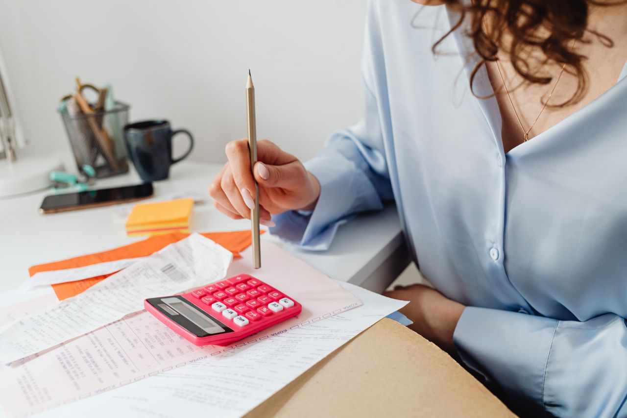 pexels photo 7680742 A woman is calculating expenses using a calculator and papers at her desk.